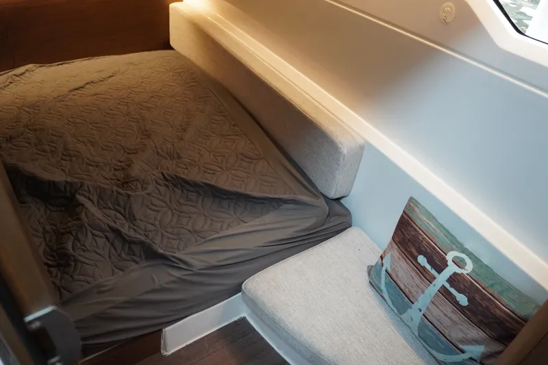 Slide: The Image of Cozy cabin interior of 2024 Jeanneau NC Sport 895 with bed and nautical-themed pillow. - 34