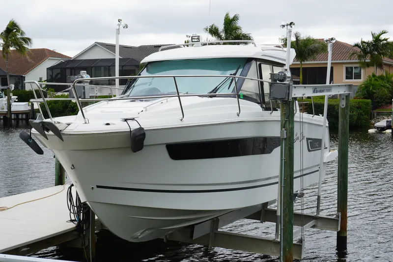 Slide: The Image of 2024 Jeanneau NC Sport 895 boat docked on a lift by waterfront homes. - 10