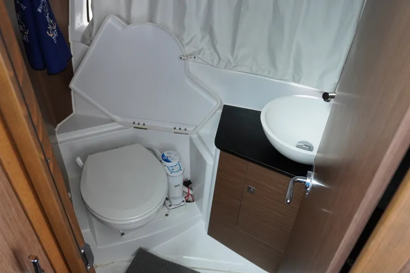 Slide: The Image of 2024 Jeanneau NC Sport 895 bathroom with toilet, sink, and wooden cabinetry. - 36