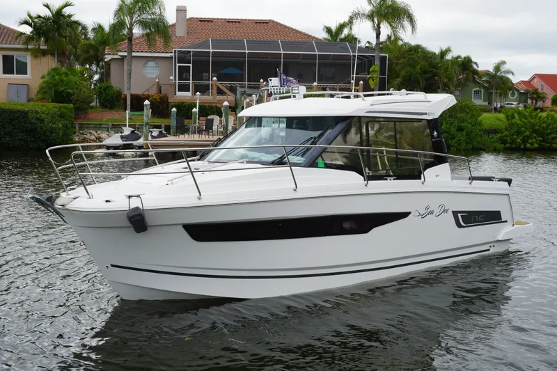 The Image of 2024 Jeanneau NC Sport 895 boat cruising on a scenic waterway near waterfront homes. - 0