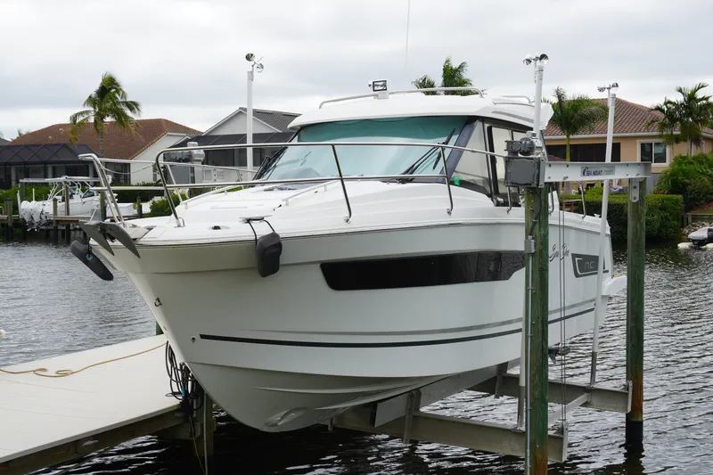 Slide: The Image of 2024 Jeanneau NC Sport 895 boat docked on a lift by waterfront homes. - 9
