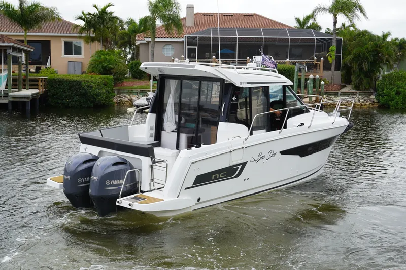 Slide: The Image of 2024 Jeanneau NC Sport 895 boat with twin Yamaha engines on a scenic waterway. - 5