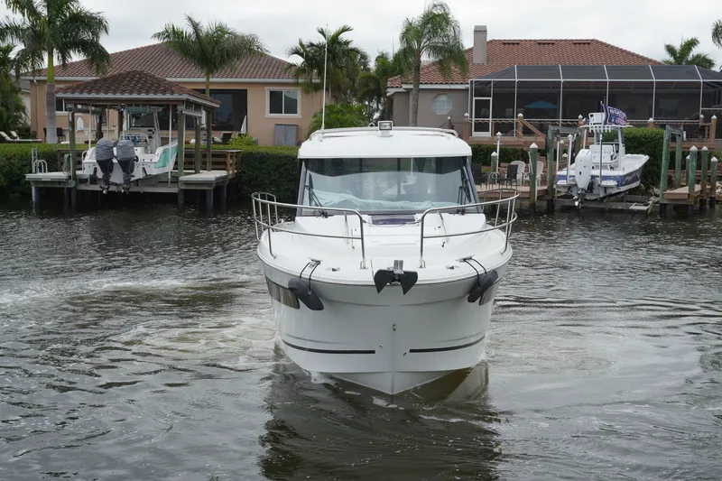 Slide: The Image of 2024 Jeanneau NC Sport 895 boat navigating near waterfront homes with docks and palm trees. - 8