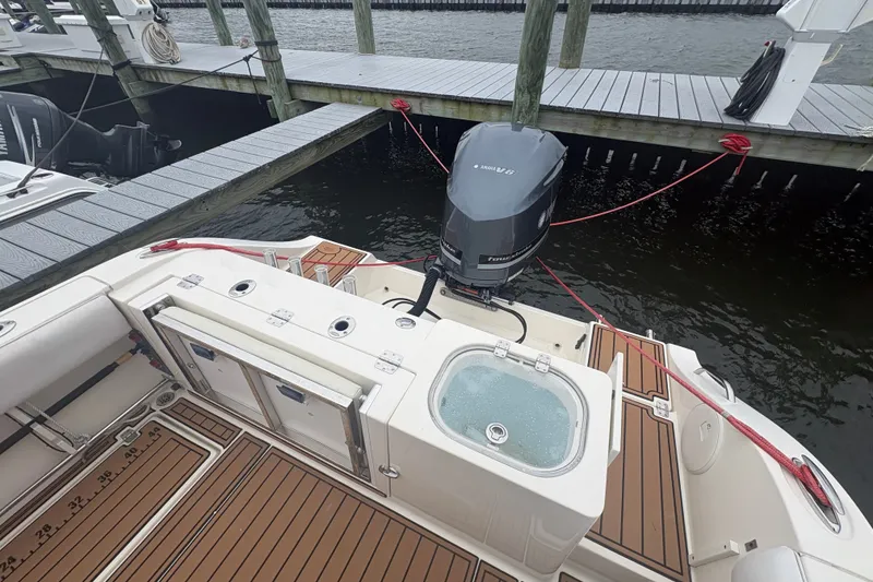 Slide: The Image of 2014 Cobia 237 Center Console boat docked, featuring Yamaha outboard motor and teak deck. - 7