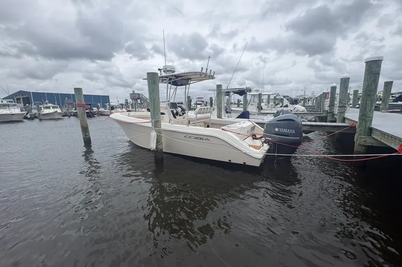 Slide: The Image of 2014 Cobia 237 Center Console boat docked at marina under cloudy skies. - 2