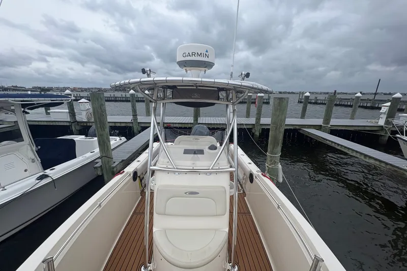 Slide: The Image of 2014 Cobia 237 Center Console boat docked, featuring Garmin equipment under cloudy skies. - 8