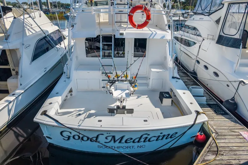 Slide: The Image of 2000 Hatteras 55 Convertible yacht docked, featuring fishing gear and "Good Medicine" name. - 14
