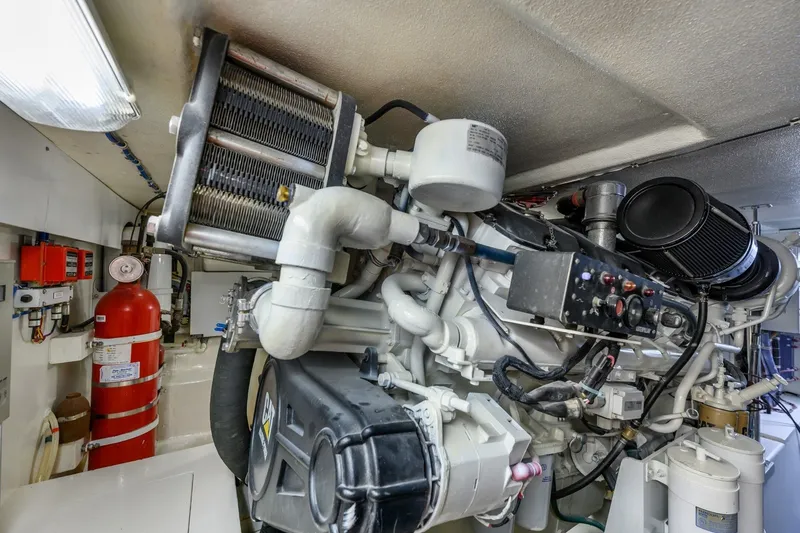 Slide: The Image of Engine room of 2000 Hatteras 55 Convertible yacht, featuring complex machinery and fire extinguisher. - 37