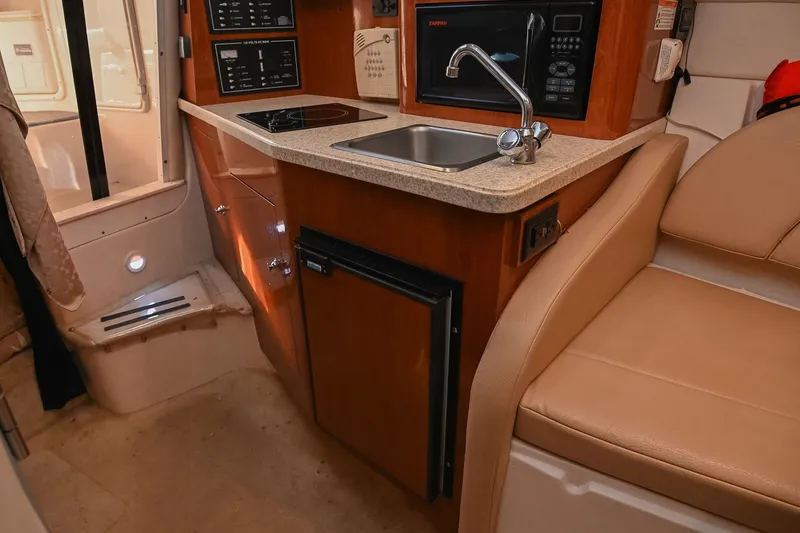 Slide: The Image of Interior of 2007 Regal Commodore 2665 boat featuring kitchenette with sink, stove, and seating. - 25