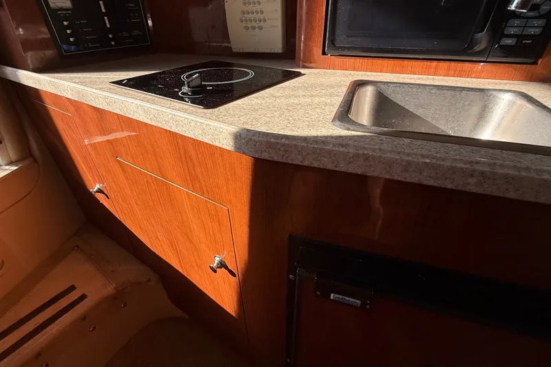 Slide: The Image of 2007 Regal Commodore 2665 boat kitchen with stove, sink, and wooden cabinetry. - 23
