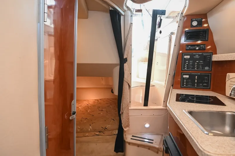 Slide: The Image of Interior of a 2007 Regal Commodore 2665 boat, featuring a compact kitchen and cozy sleeping area. - 34