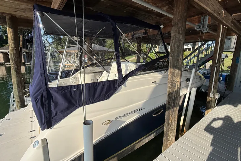 Slide: The Image of 2007 Regal Commodore 2665 boat docked under wooden shelter with blue canopy. - 10