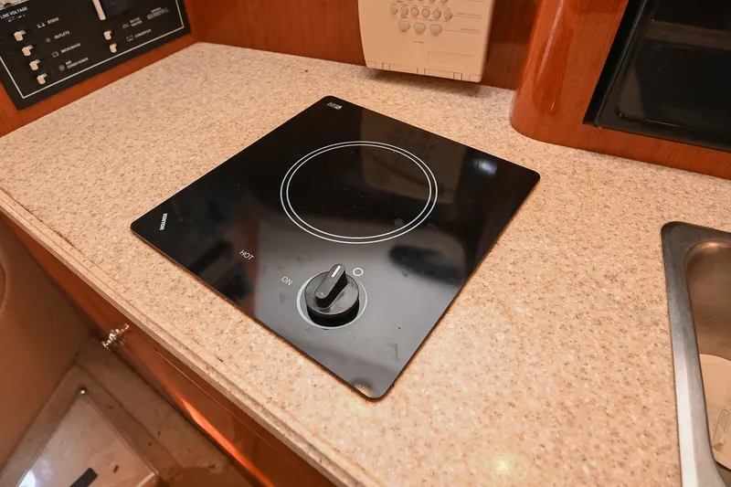 Slide: The Image of 2007 Regal Commodore 2665 boat interior with a sleek black cooktop on a beige countertop. - 26