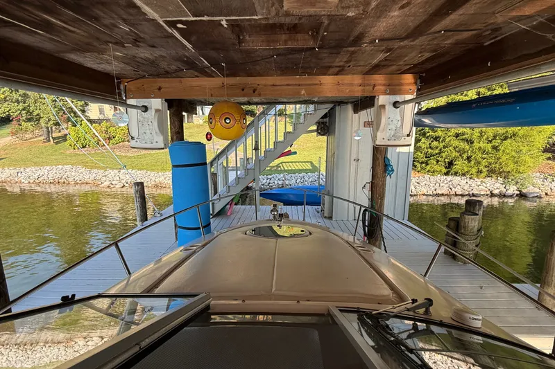 Slide: The Image of Boat docked under wooden shelter, Regal Commodore 2665, 2007 model, near a scenic lakeside. - 28