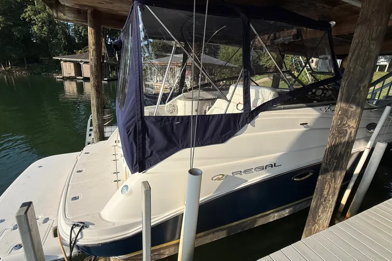Slide: The Image of 2007 Regal Commodore 2665 boat docked under a wooden shelter on a serene lake. - 11