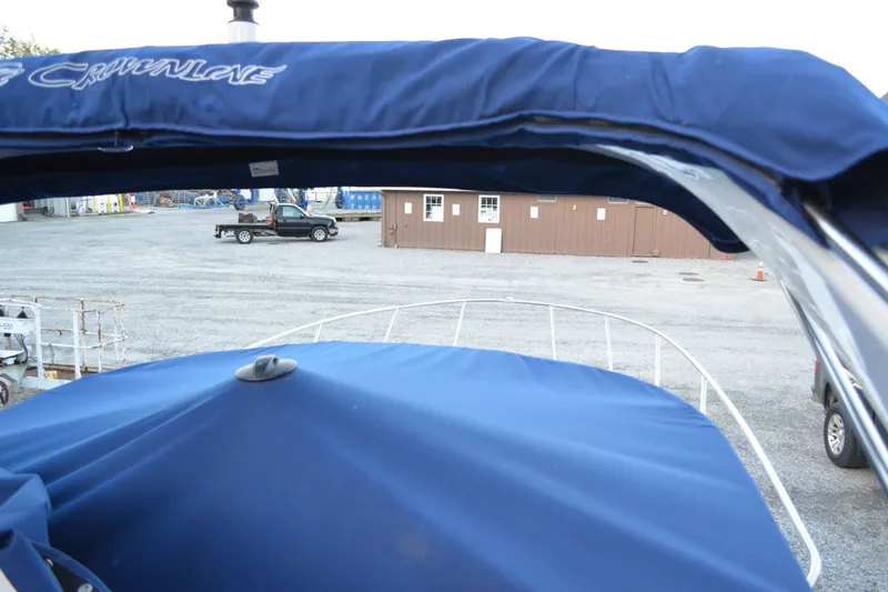 Slide: The Image of 2024 Crownline 270 CR boat with blue canopy in a marina setting. - 3