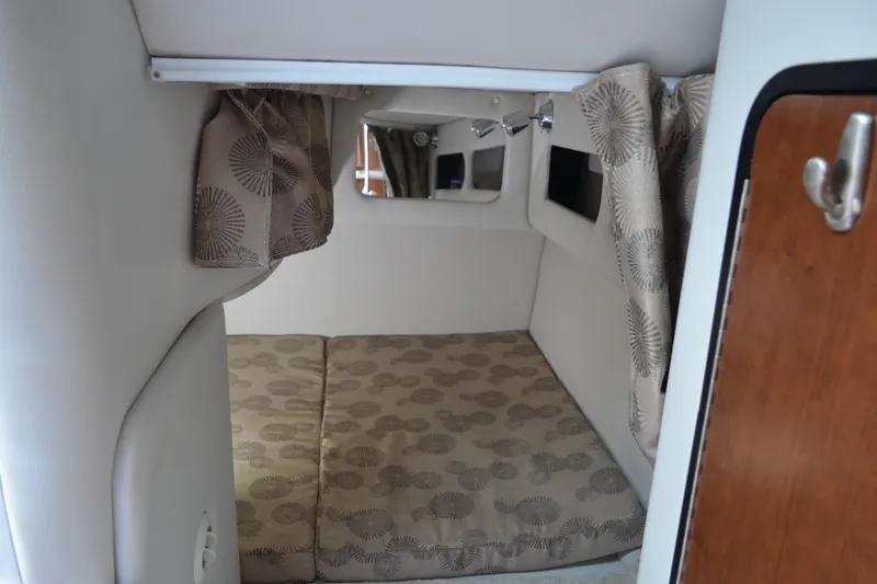 Slide: The Image of 2024 Crownline 270 CR cabin interior with patterned cushions and curtains. - 25
