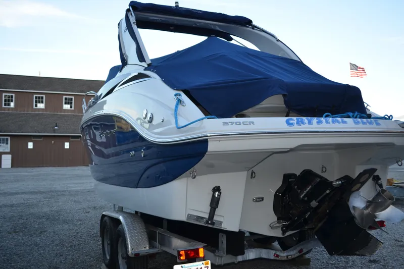 Slide: The Image of 2024 Crownline 270 CR boat on trailer, covered, with "Crystal Blue" name visible. - 2