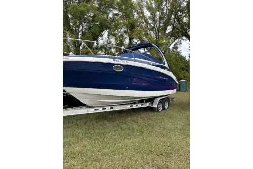 Slide: The Image of A blue and white 2024 Crownline 270 CR boat on a trailer in a grassy area. - 36
