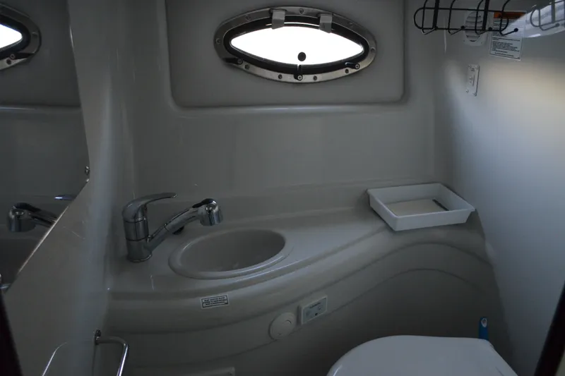 Slide: The Image of 2024 Crownline 270 CR boat bathroom with sink, faucet, and porthole window. - 26