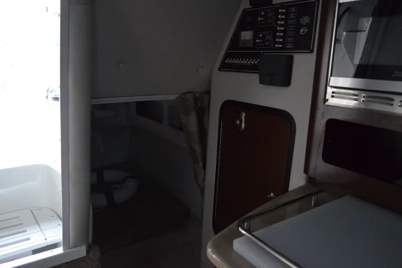 Slide: The Image of 2024 Crownline 270 CR cabin interior with control panel and compact kitchen area. - 22
