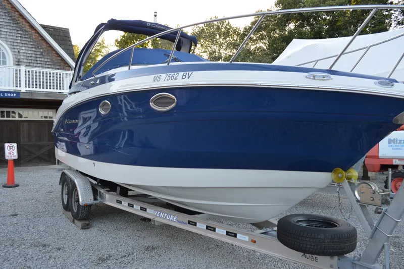 Slide: The Image of 2024 Crownline 270 CR boat on trailer, blue and white exterior, parked outdoors. - 1