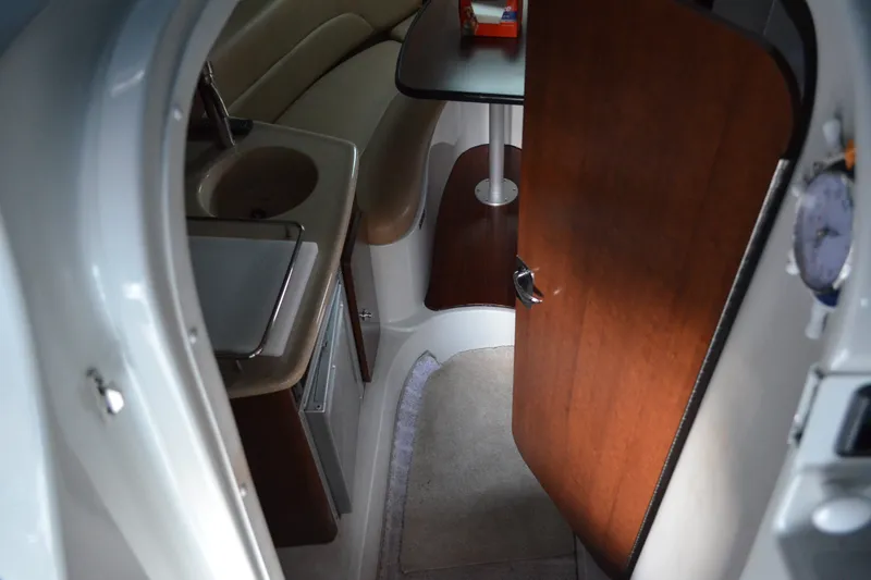 Slide: The Image of Interior of 2024 Crownline 270 CR boat, featuring compact kitchenette and seating area. - 18