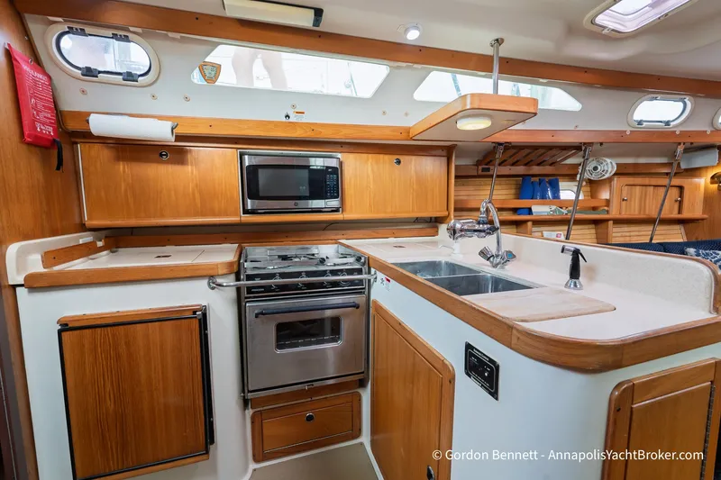 Slide: The Image of Luxurious 2003 Catalina 380 yacht kitchen with wood cabinetry, stove, and sink. - 29