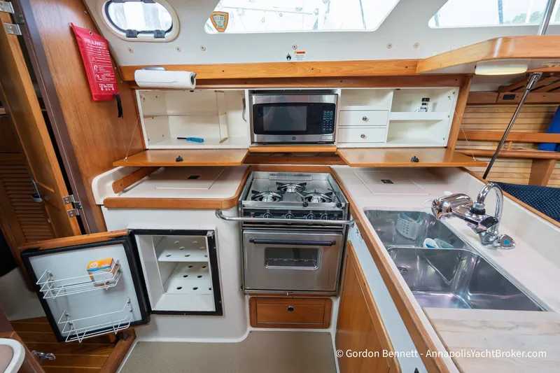 Slide: The Image of 2003 Catalina 380 yacht kitchen with stove, microwave, sink, and open fridge. - 30