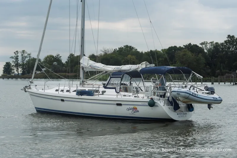 Slide: The Image of 2003 Catalina 380 sailboat anchored on calm water with inflatable dinghy attached. - 7