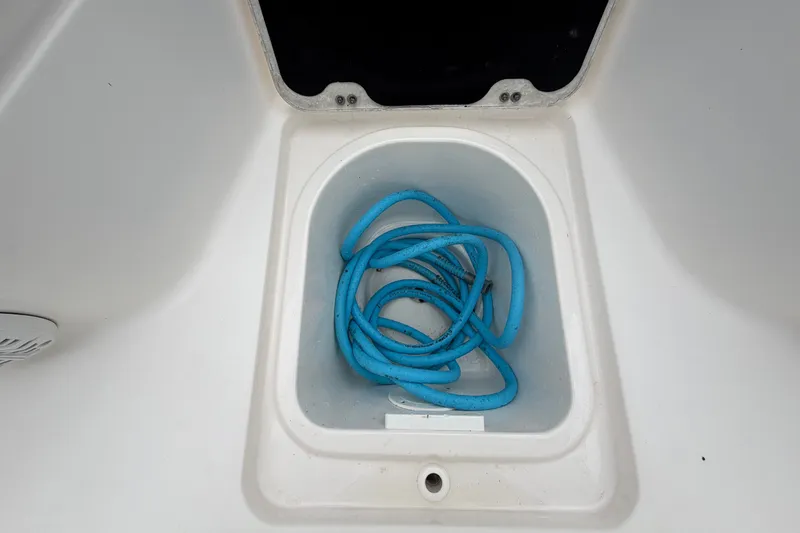 Slide: The Image of A blue hose is coiled in a white storage compartment on a boat. - 42