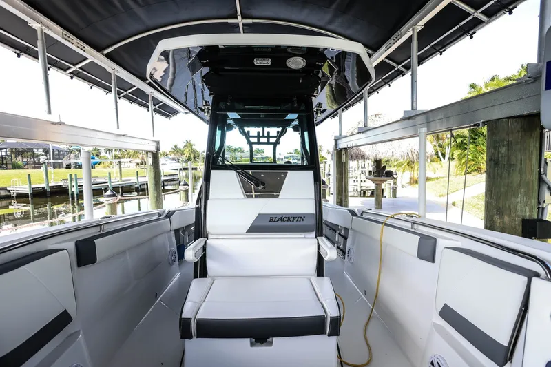 Slide: The Image of 2019 Blackfin 272 CC boat interior with seating and canopy in a marina setting. - 15