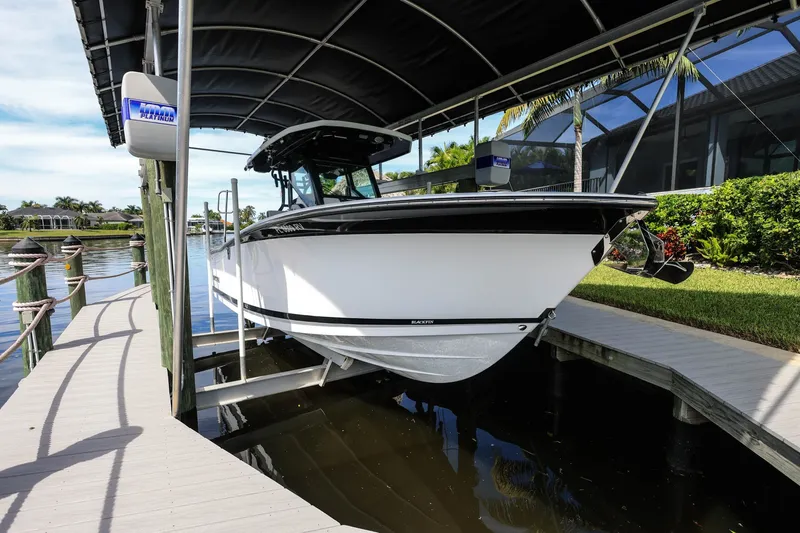 Slide: The Image of 2019 Blackfin 272 CC boat docked under a canopy in a scenic marina. - 1