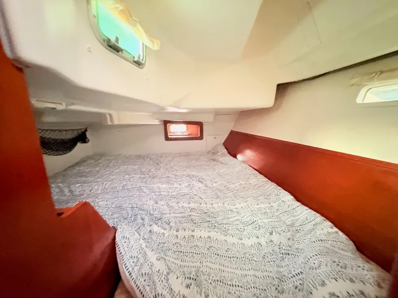 Slide: The Image of The cabin of the 2005 Beneteau Oceanis Clipper 343 features a cozy bed with wood accents. - 32