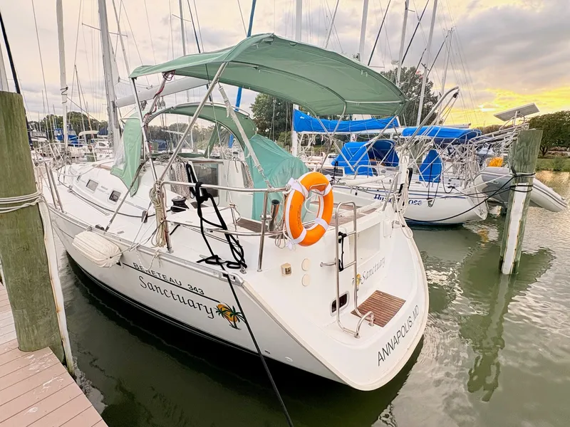 Slide: The Image of A 2005 Beneteau Oceanis Clipper 343 docked. It features a green sunshade and a lifebuoy. - 3