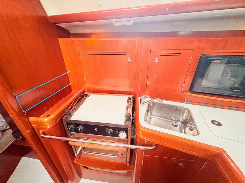 Slide: The Image of The galley of a 2005 Beneteau Oceanis Clipper 343 with a stove, sink, and wooden cabinets. - 30