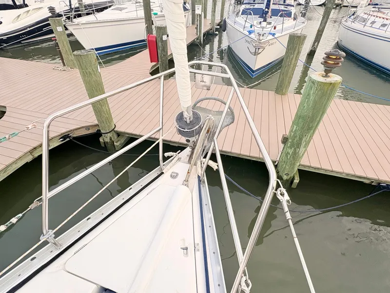 Slide: The Image of The bow of a sailboat in a marina, surrounded by other boats and wooden docks. - 11