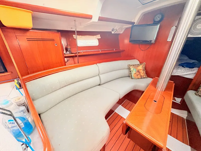 Slide: The Image of Interior of a 2005 Beneteau Oceanis Clipper 343 with a curved sofa and wooden table. - 26
