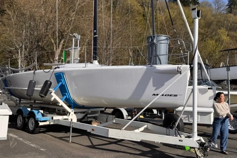 Slide: The Image of 2008 Melges 32 sailboat on trailer, parked outdoors with trees in background. - 7