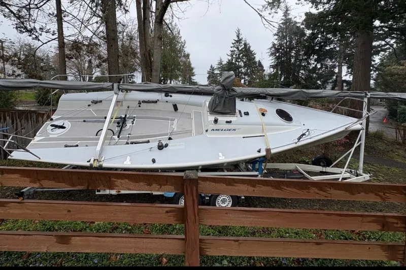Slide: The Image of 2008 Melges 32 sailboat on trailer, surrounded by trees and wooden fence. - 3