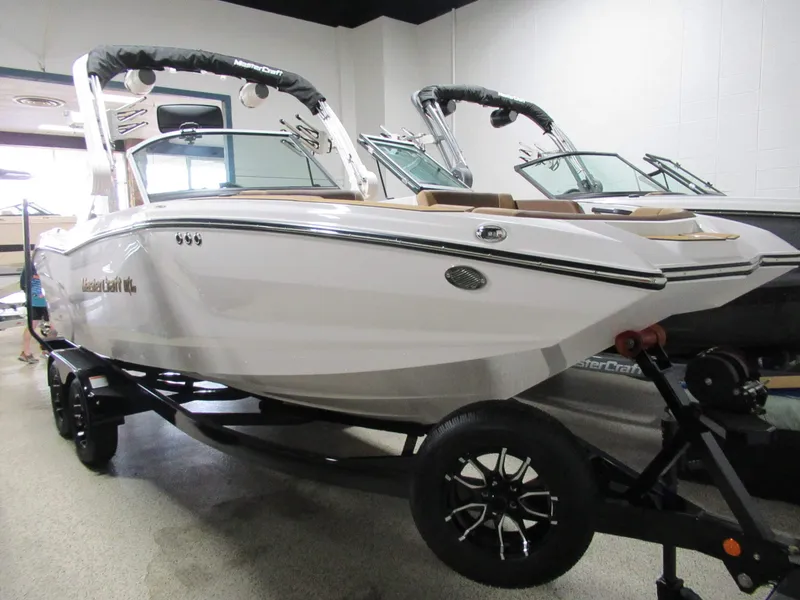 The Image of 2027 MasterCraft NXT22: Sleek design, white hull, on a trailer in a showroom. - 1