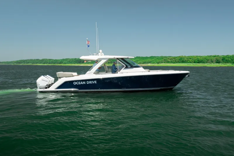 The Image of 2022 Tiara Yachts 38 LS cruising on a serene lake with lush green shoreline. - 1