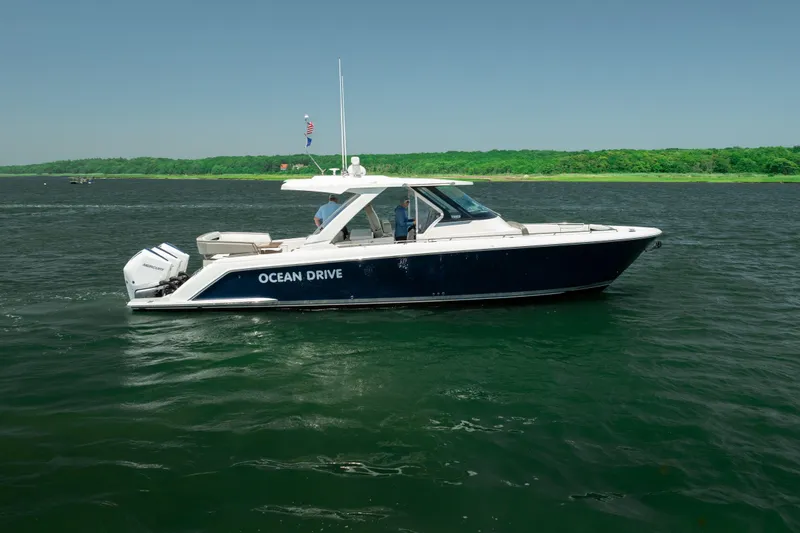 Slide: The Image of 2022 Tiara Yachts 38 LS cruising on a serene lake with lush green shoreline. - 15