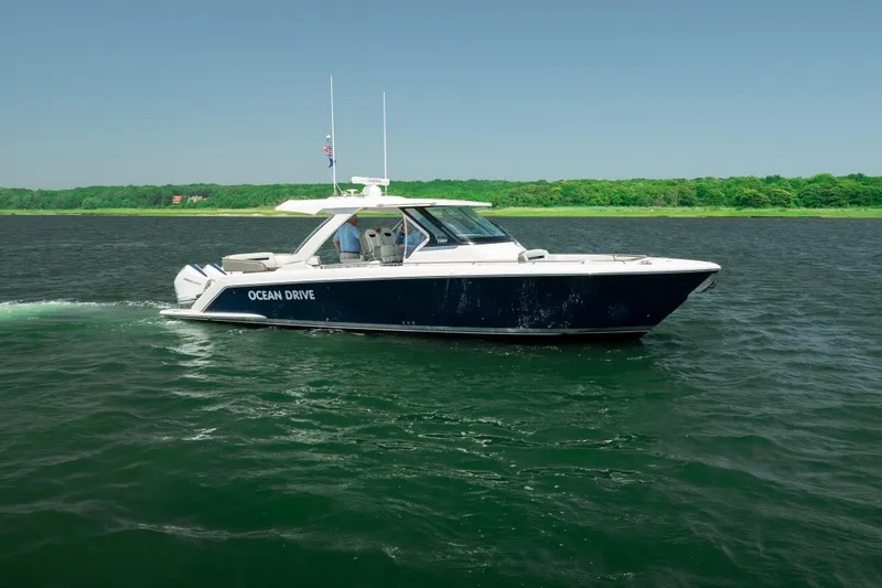 Slide: The Image of 2022 Tiara Yachts 38 LS cruising on open water, lush green shoreline in background. - 14