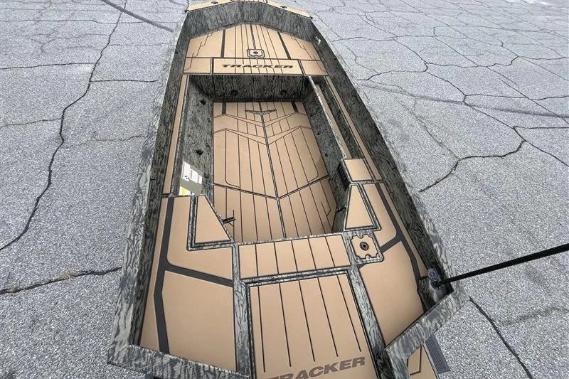 Slide: The Image of 2027 Tracker Grizzly 1553 Timber boat with camouflage design on cracked pavement. - 14