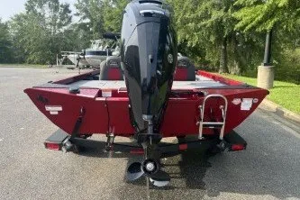 Slide: The Image of 2027 Ranger RT178 boat, red exterior, parked outdoors, rear view with motor and ladder. - 2