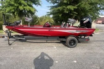 The Image of 2027 Ranger RT178 boat in vibrant red, parked on a trailer, surrounded by trees. - 0