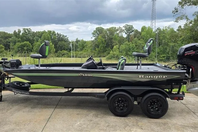 Slide: The Image of 2027 Ranger RT198P fishing boat on trailer, parked outdoors with lush greenery background. - 1