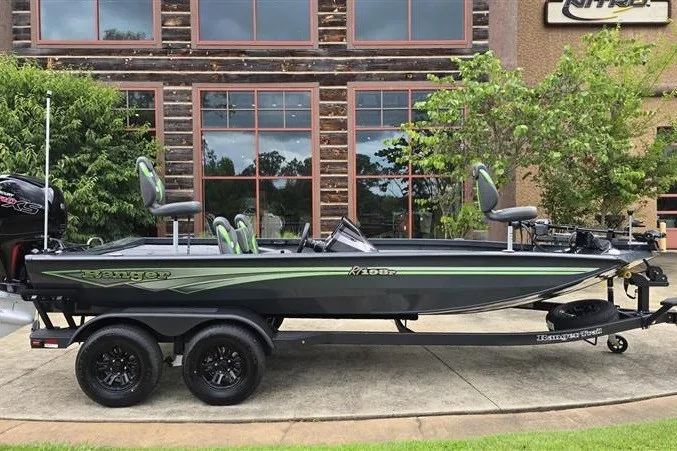 Slide: The Image of 2027 Ranger RT198P fishing boat on trailer, parked outside rustic building. - 6