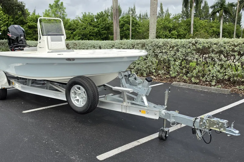 The Image of 2026 Mako 18 Pro Skiff boat on trailer in parking lot, surrounded by greenery. - 0